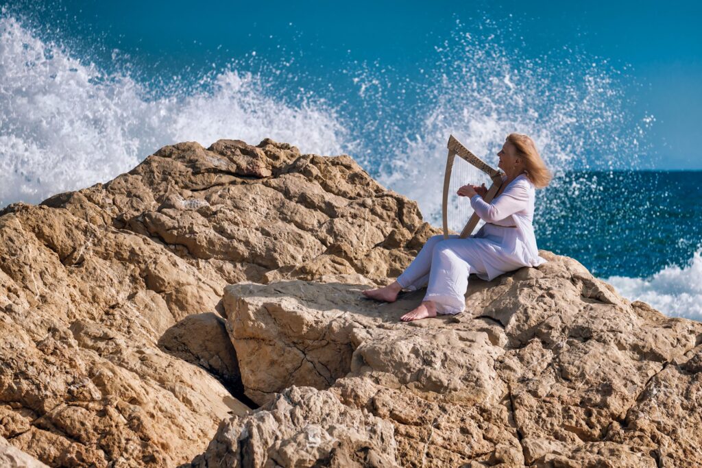 Ani playing the harp on the edge of the ocean